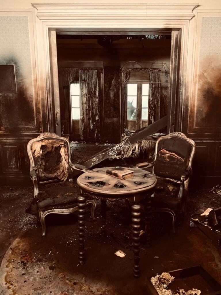 Salón quemado con butacas y una mesa calcinadas