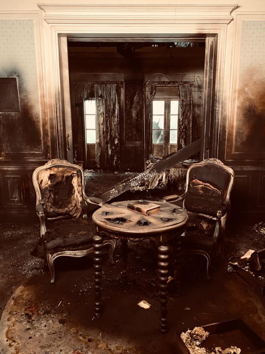Salón quemado con butacas y una mesa calcinadas