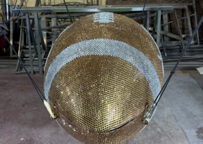 Balón gigante de pedrería dorada y plateada colgado en el taller