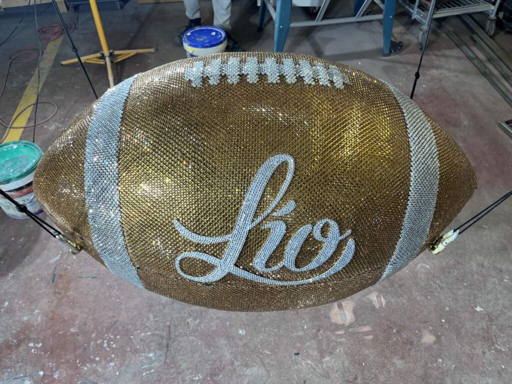 Balón de fútbol americano gigante cubierto de pedrería dorada