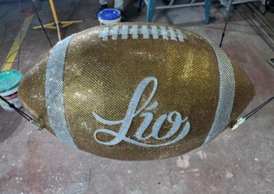 Balón de fútbol americano gigante cubierto de pedrería dorada