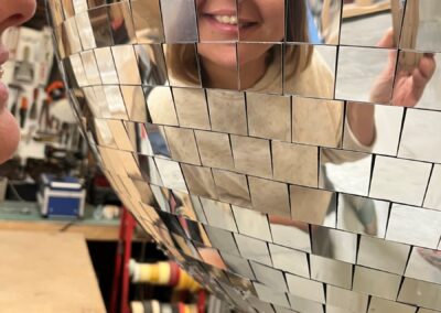 Persona reflejada en los espejos de una bola de discoteca gigante