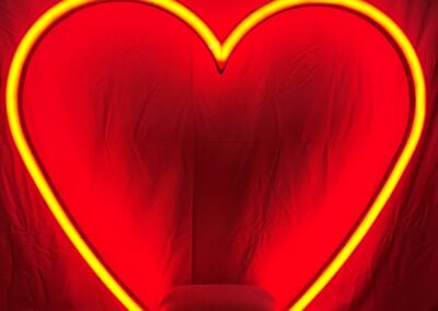 Columpio con forma de corazón de neón encendido y asiento tapizado en rojo