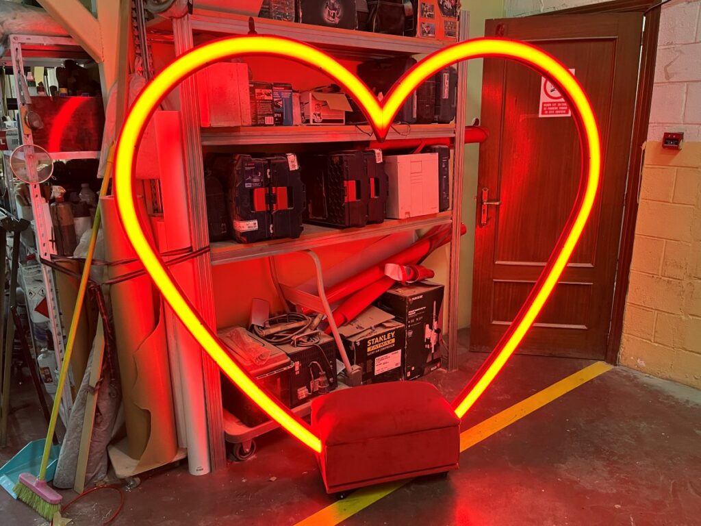 Columpio con forma de corazón de neón rojo y asiento tapizado en el taller