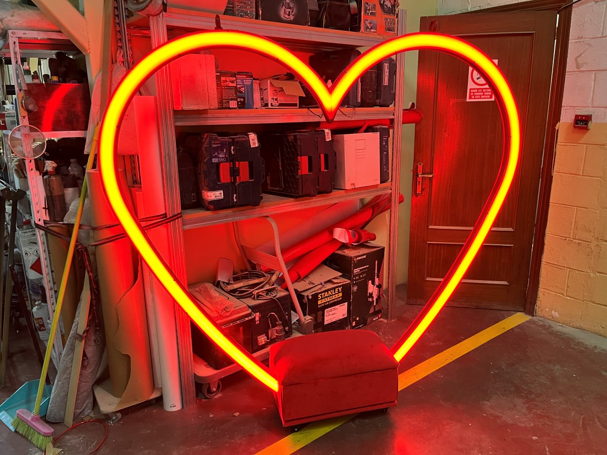 Columpio con forma de corazón de neón rojo y asiento tapizado en el taller