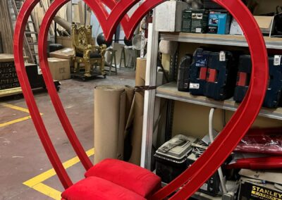 Estructura roja del columpio corazón con asiento de terciopelo, en el taller