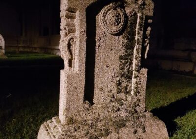 Lápida de piedra con musgo sobre la hierba, de noche