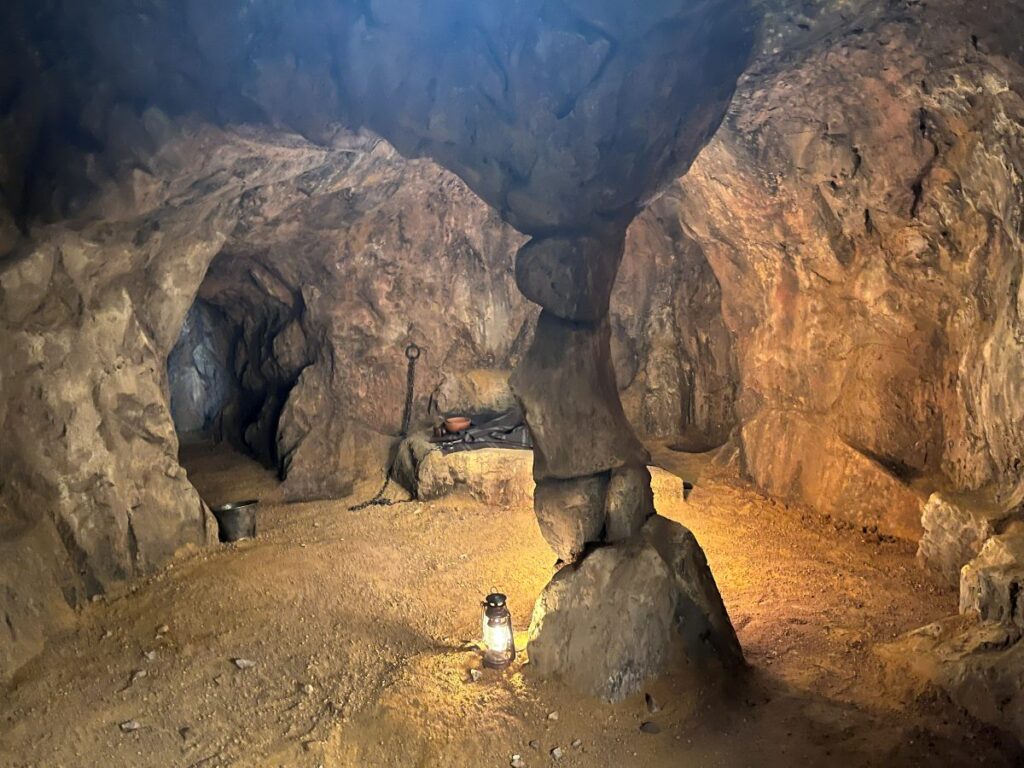 Interior de una cueva de roca construida en plató, iluminada con un farol en el suelo