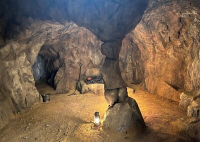 Interior de una cueva de roca construida en plató, iluminada con un farol en el suelo
