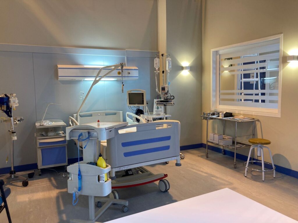 Habitación de hospital con cama articulada, monitores y ventana interior