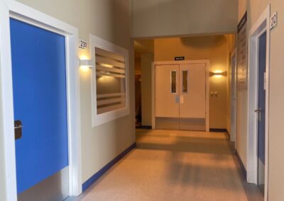 Pasillo de hospital con puertas azules y doble puerta al fondo