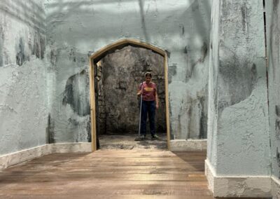 Pasillo de muros de piedra desconchados con un arco al fondo, construido en plató
