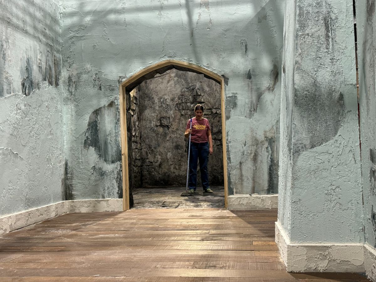 Pasillo de muros de piedra desconchados con un arco al fondo, construido en plató