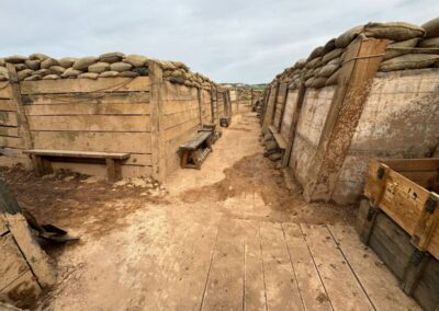 Trinchera con bancos de madera y cajas, entre paredes de tablones y sacos terreros
