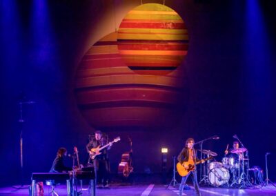 Quique González y su banda en concierto bajo un gran sol de franjas de colores