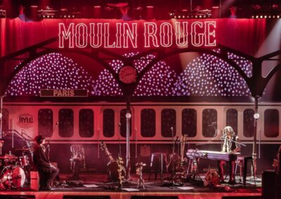 Escenografía de vagón de tren con el rótulo luminoso Moulin Rouge