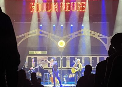 Rulo y la Contrabanda en concierto bajo un arco de estación iluminado, visto desde el público