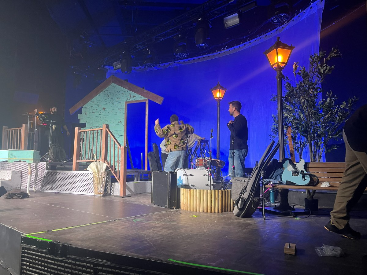 Concierto con la casita de madera turquesa y la farola encendida sobre fondo azul