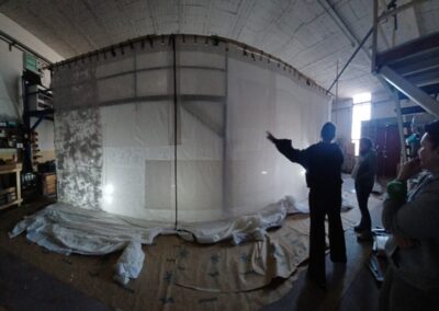 Equipo revisando el telón pintado colgado en la nave