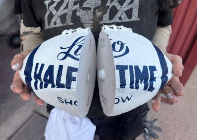Balón blanco Lío Half Time Show abierto en dos mitades, sujeto con las manos