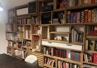 Librería de madera a medida instalada en una pared, llena de libros y juegos