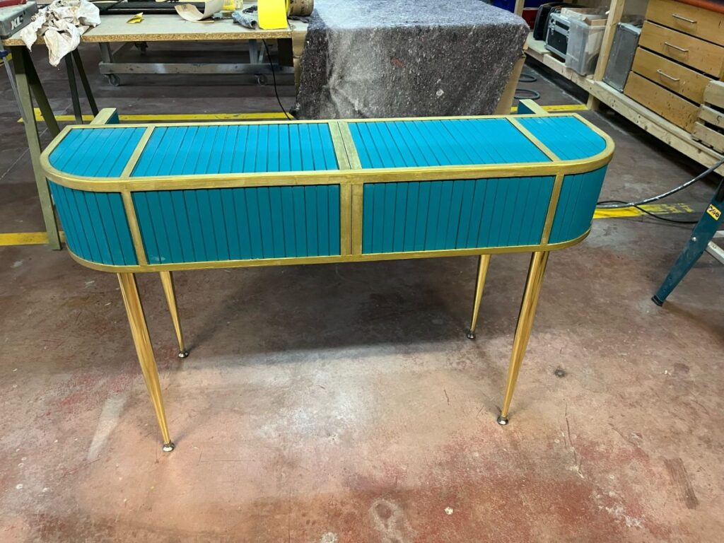Mueble soporte para teclado con laterales tapizados en azul y patas doradas