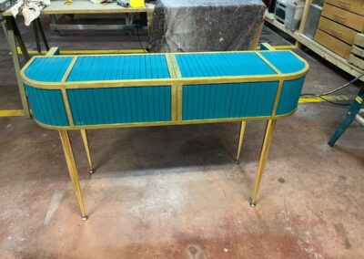 Mueble soporte para teclado con laterales tapizados en azul y patas doradas