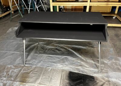 Soporte de teclado negro con patas metálicas, en el taller