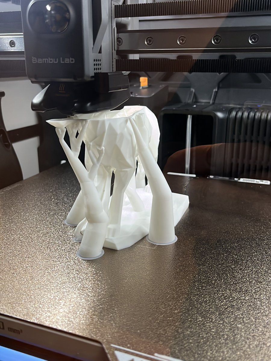 Impresora 3D fabricando una pieza blanca con soportes
